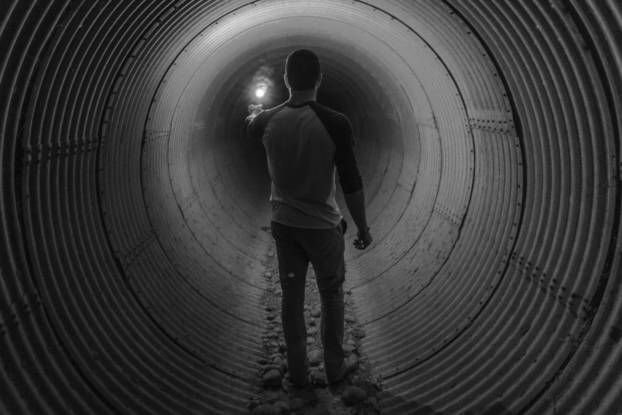 Man holding light walking inside tunnel